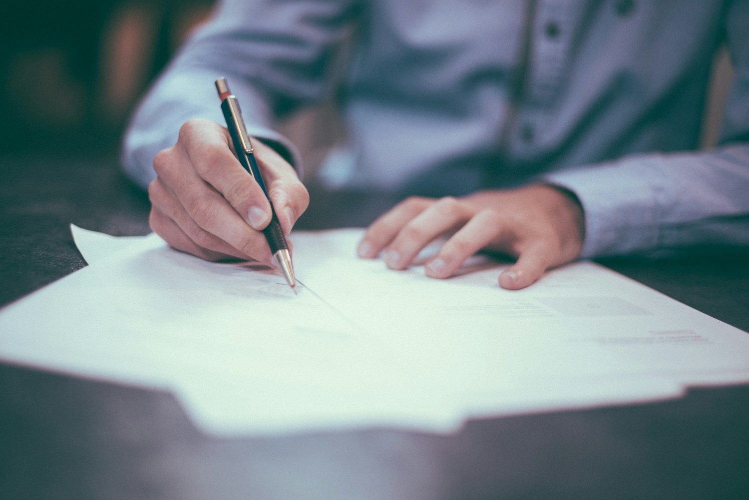 A person writing on a business document
